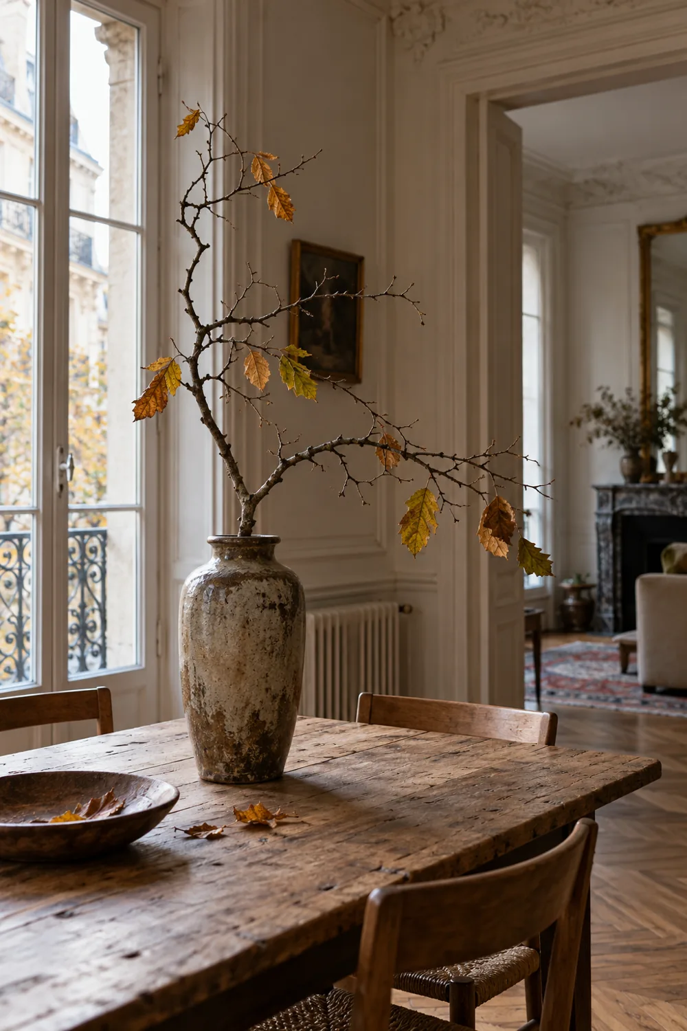 Branche tombée aux feuilles d’automne dans un vase ancien sur une table